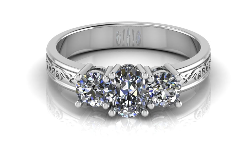 White gold three stone engagement ring featuring a claw set oval cut diamond with two side round diamonds and swirl motif