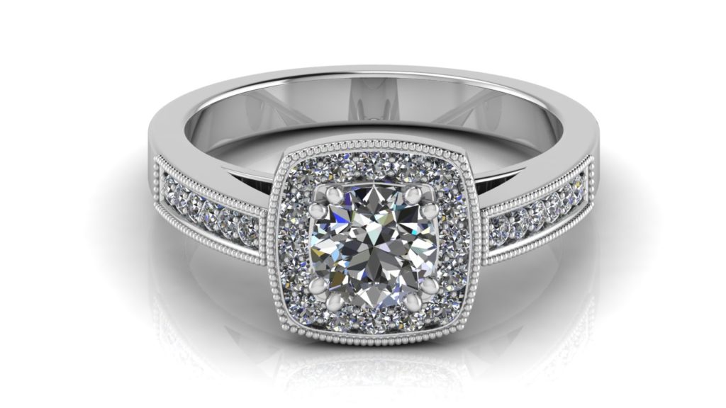 White gold cushion halo engagement ring featuring a double claw set round diamond with smaller pave set diamonds down the band and milgrain accents