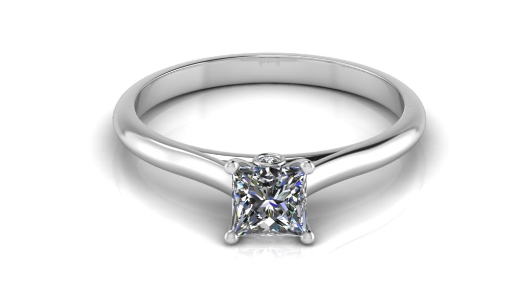 White gold solitaire engagement ring featuring a princess cut diamond with a bezel set accent diamond